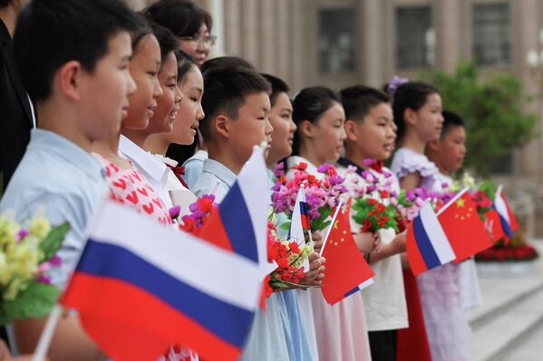 Дети, держат российский и китайский флаги перед церемонией приветствия президента России Владимира Путина в Доме народных собраний в Пекине