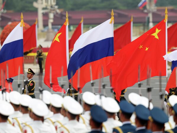 Почетный караул Народно-освободительной армии Китая (НОА) держат китайские и российские флаги перед церемонией приветствия президента России.